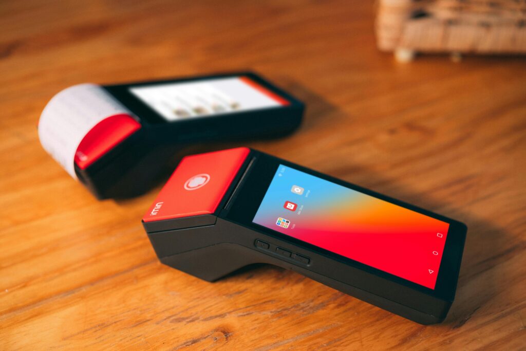 Close-up of two modern cashless payment terminals on a wooden surface, showcasing digital technology.